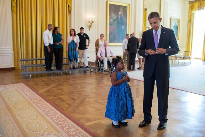 President Barack Obama writes a school excuse note for Alanah Poullard, 5, while visiting with Wounded Warriors and their families in the East Room