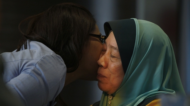 A journalist kisses Wan Tom Wan Chik, the mother of 33 year old Malaysia Airlines flight MH370 passenger Mohd Sofuan Razak after interview.